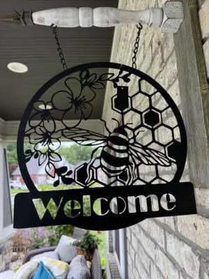 Metal bee welcome sign on porch