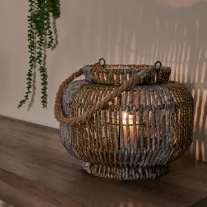 Woven rope lantern with lit candle on table