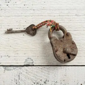 Rusty padlock with key on wooden surface