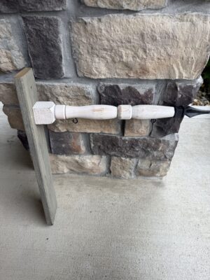 White turned wooden spindle clamped to post