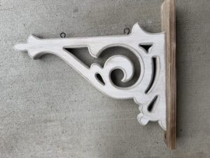 White ornate wooden corbel bracket on concrete