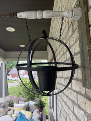 Black spherical hanging planter on porch