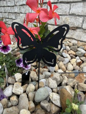 Black metal butterfly garden stake among rocks