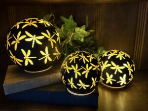 Three glowing dragonfly-patterned spherical lamps