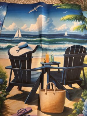 Two beach chairs with sunhat, drinks, sailboats