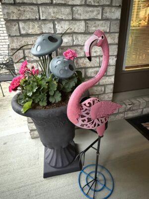 Pink flamingo garden ornament beside flowering planter